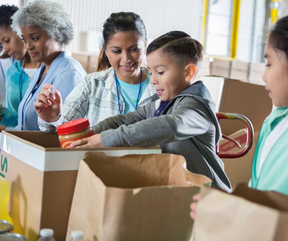 This is a photo of a child helping adults pack up a food hamper.