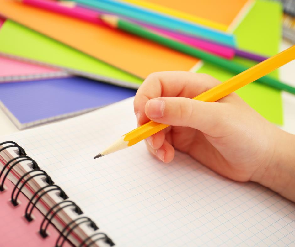 This is an image of a child writing in a notebook