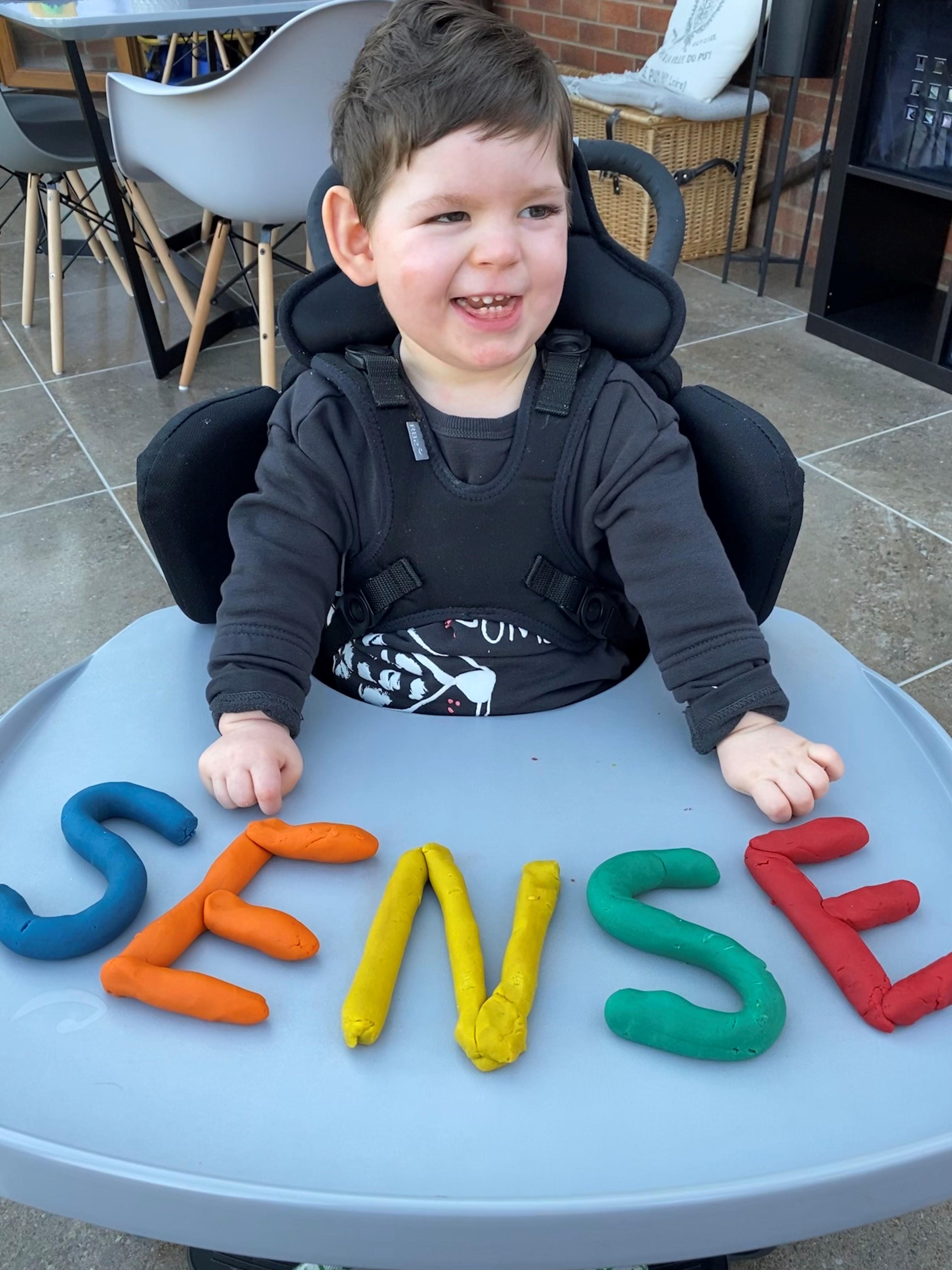 Charlie sitting in his chair with Sense spelt out in PlayDough