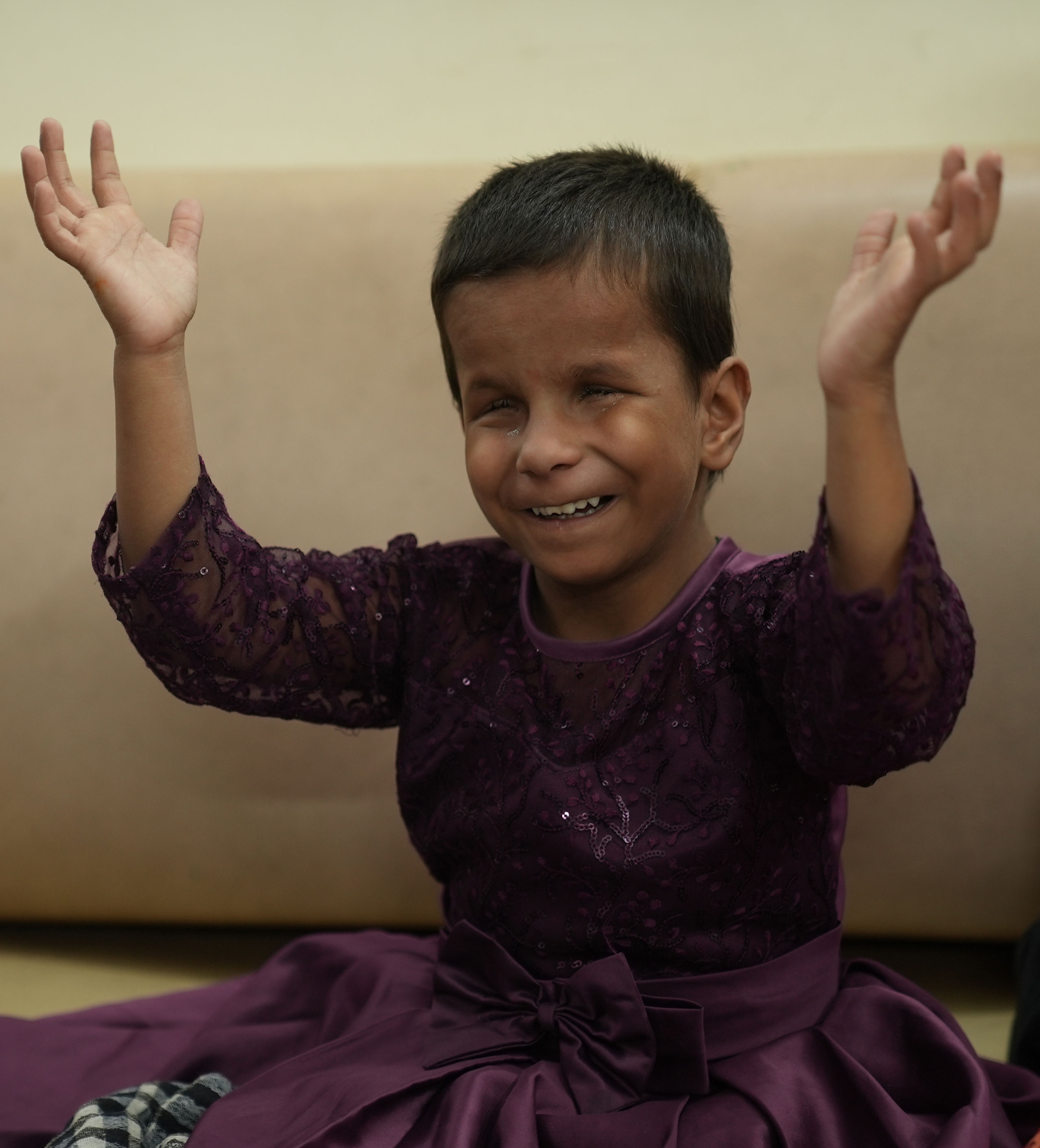 A young girl wearing a dress with her arms outstretched.