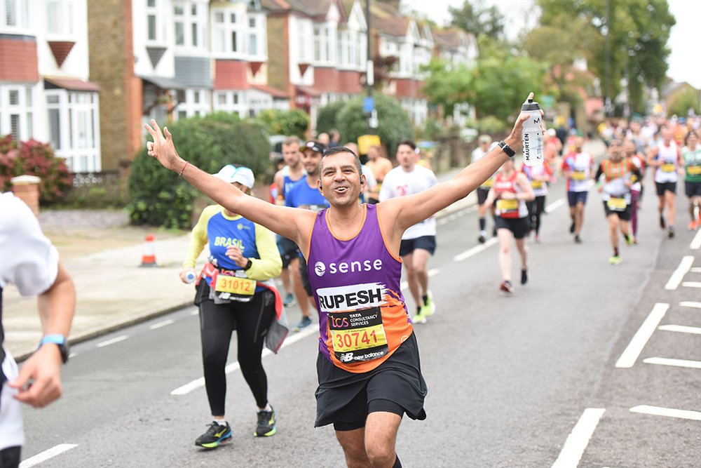 A man in a running vest holding his hands up