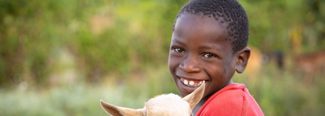 Smiling boy holding a goat