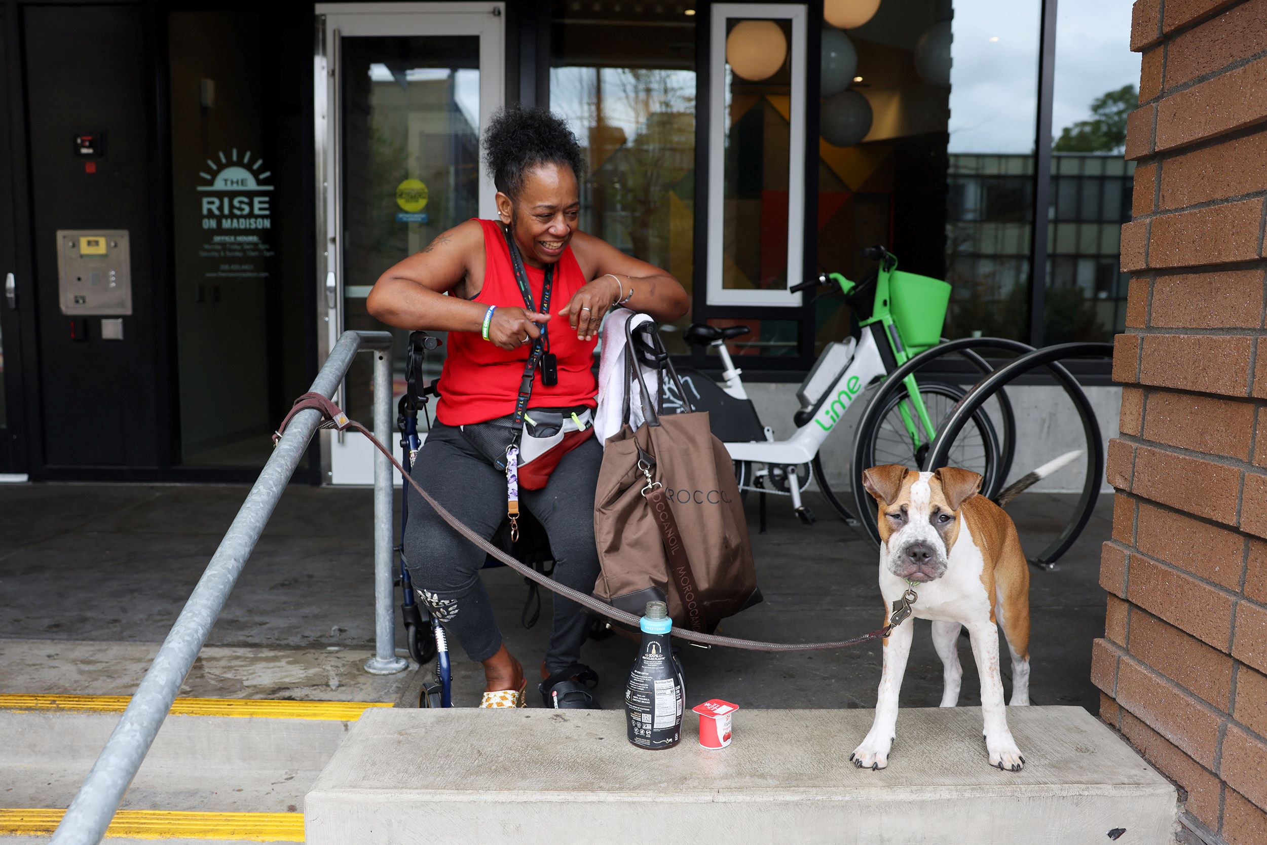 A person and a dog sit on the steps of an apartment complex.