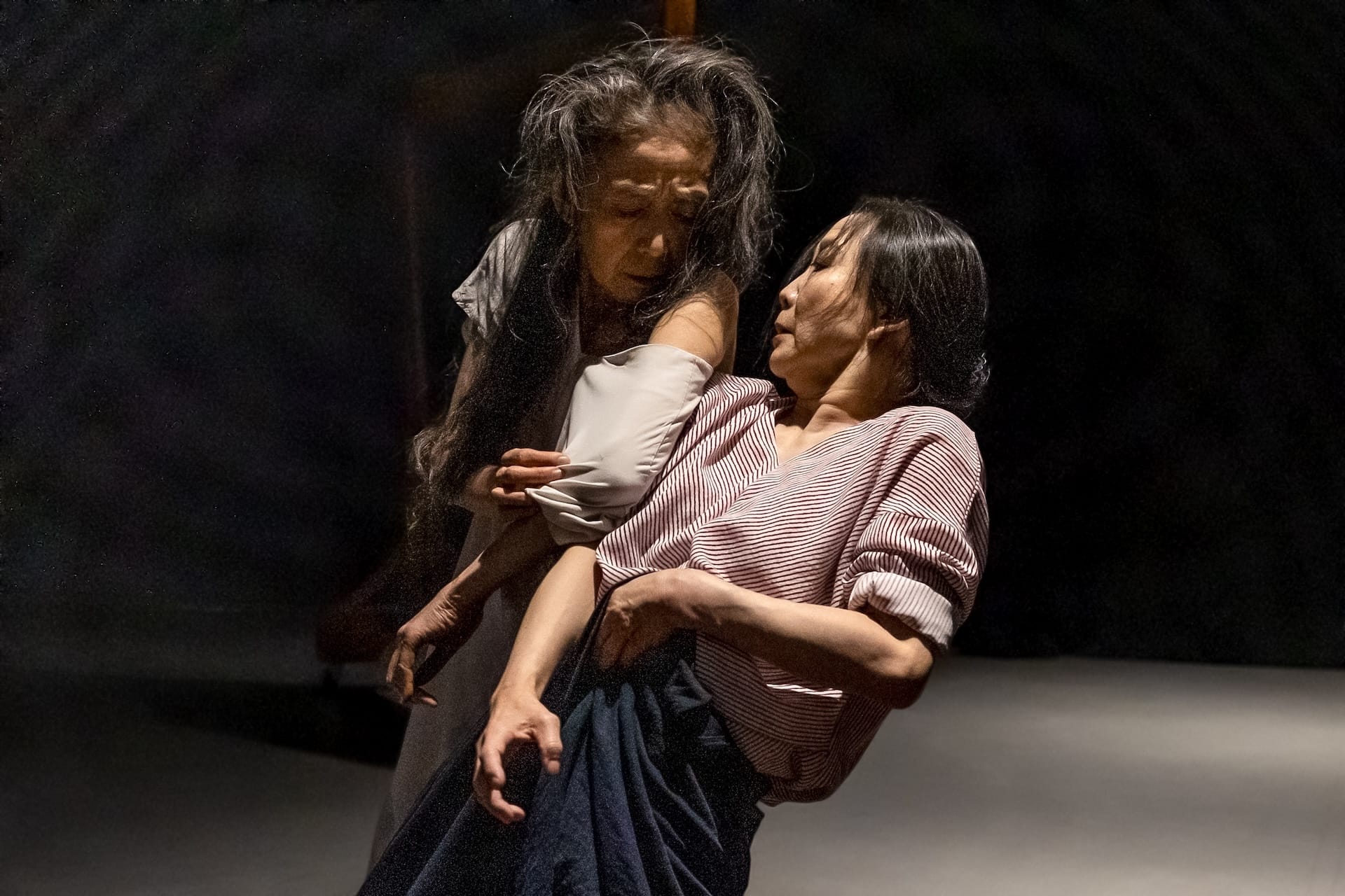 Two people lean against one another on stage