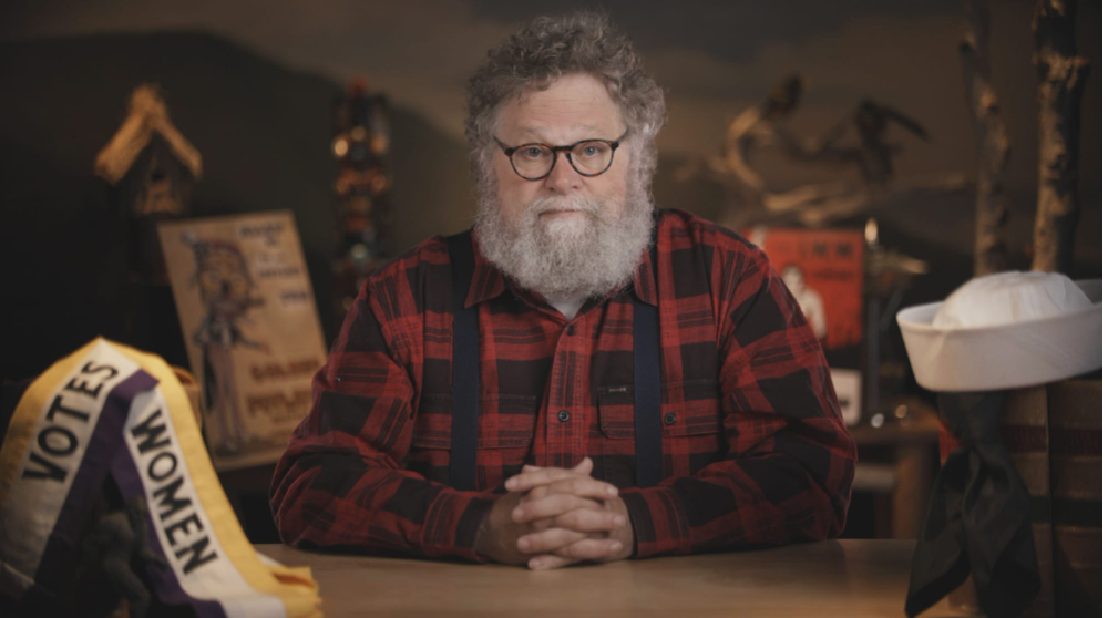 Knute Berger sits at a desk wearing a lumberjack flannel