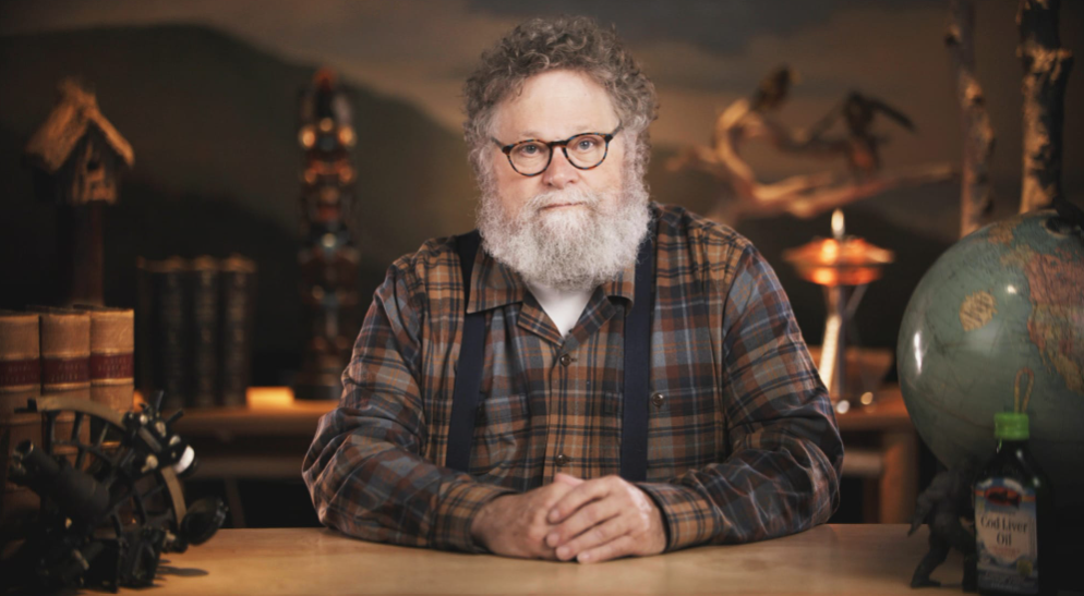 Knute Berger sits at a desk wearing a lumberjack flannel