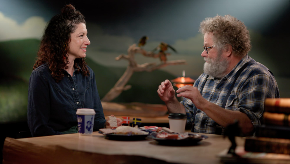 Rachel Belle and Knute Berger sit talking at a table with food on it