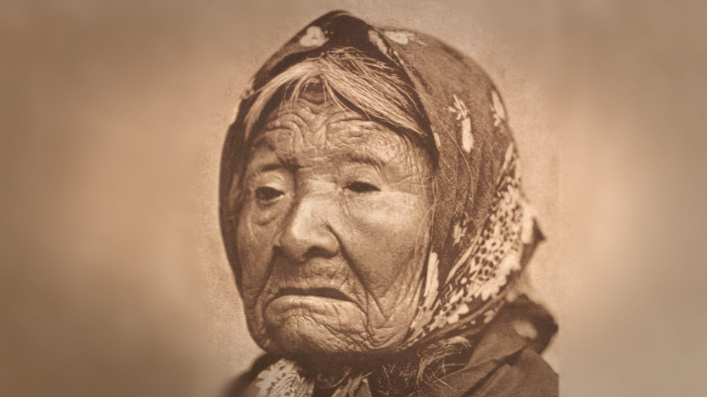 A black-and-white photo of an elderly woman wearing a head kerchief