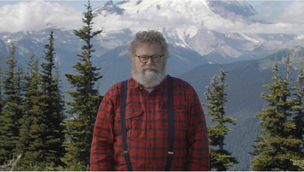 Knute Berger stands in front of Mount Rainier and trees