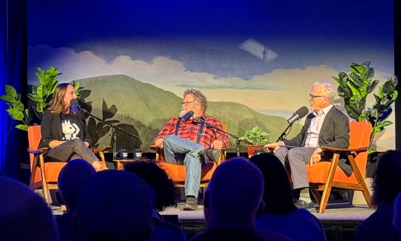 Three people sit on stage talking
