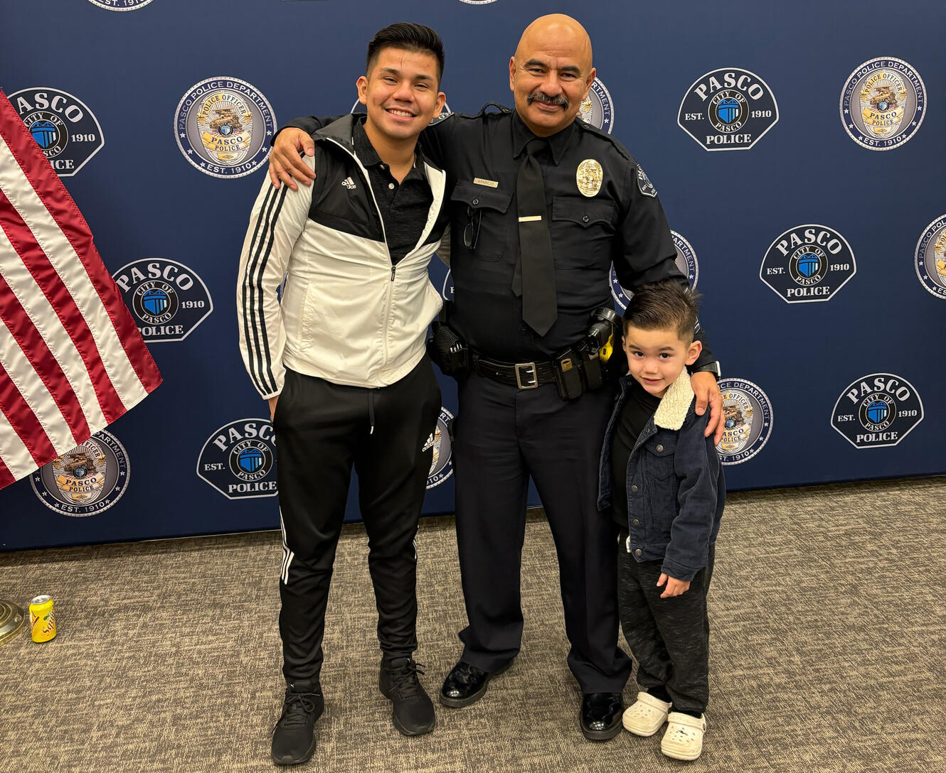 A police officer stands with his arms around his family at a swearing in ceremony.