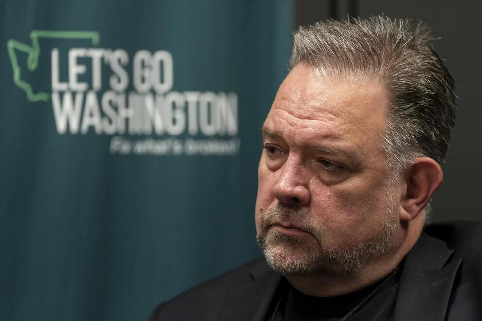 Brian Heywood sitting in front of a Let's Go Washington logo.