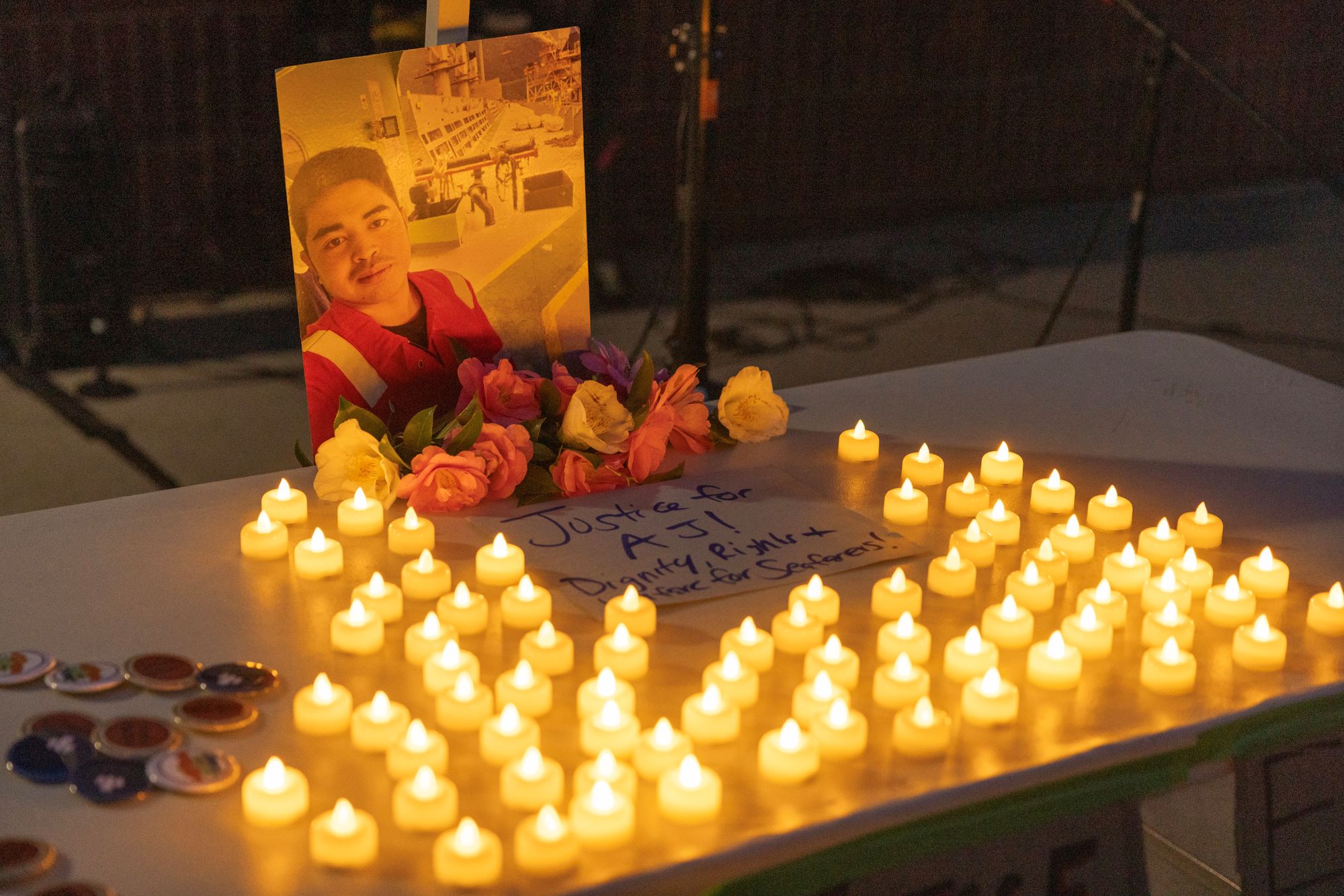 Vigil candles and flowers gathered around a photo of a young person