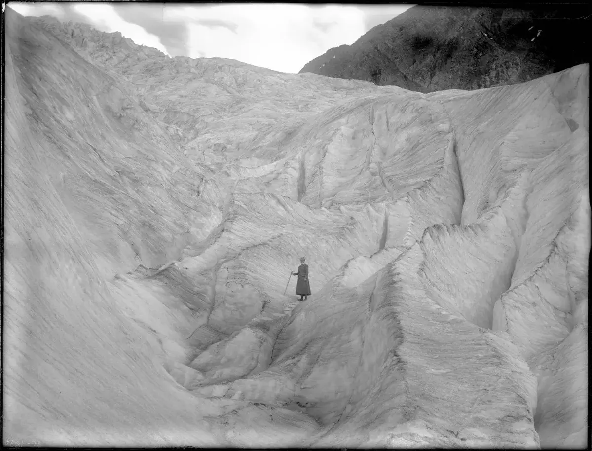 A black-and-white photo of a woman standing on a glacier.