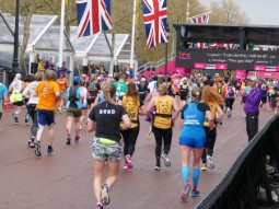 A photo of a group of runners approaching the finish line of the London Marathon - two of the runners are wearing yellow Born Free running vests