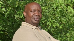 A headshot of Charles Njoroge standing in front of a natural background.