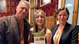 Photograph of Chris Packham stood with a young girl holding a poster, and author Chloe Dalton
