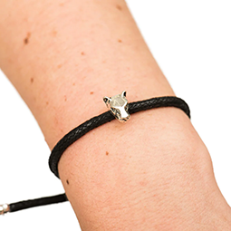Close up of a woman's wrist wearing a black bracelet with silver lion head