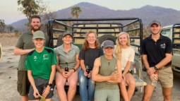 A photo of a group of volunteers in Malawi, sitting on the back of a truck with mountains in the background.