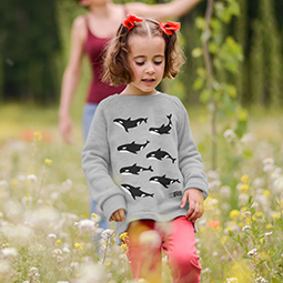 A young girl in a grey sweatshirt with orca print