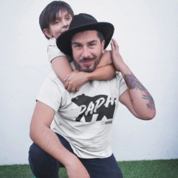 A man wearing a Born Free 'Papa Bear' T-shirt, with a young boy hugging him from behind