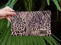 A photo of a woman's hand holding a pencil case which features various animal print in black, on a beige background. The Born Free logo is printed bottom right.