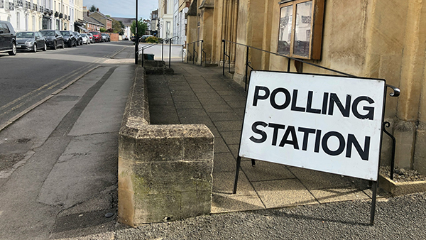 A metal A-frame sign reading 'polling station' in front of a building