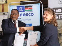 A photo Dr James Njogu shaking hands with Born Free MD, Karen Botha, in front of banners.