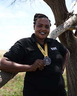 Elizabeth from the Born Free Kenya team, wearing a black Born Free shirt and holding a Walk on the Wild Side medal around her neck.