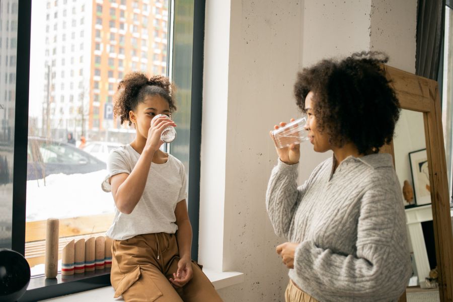 Image of two people a mom and a daughter drinking glass of water