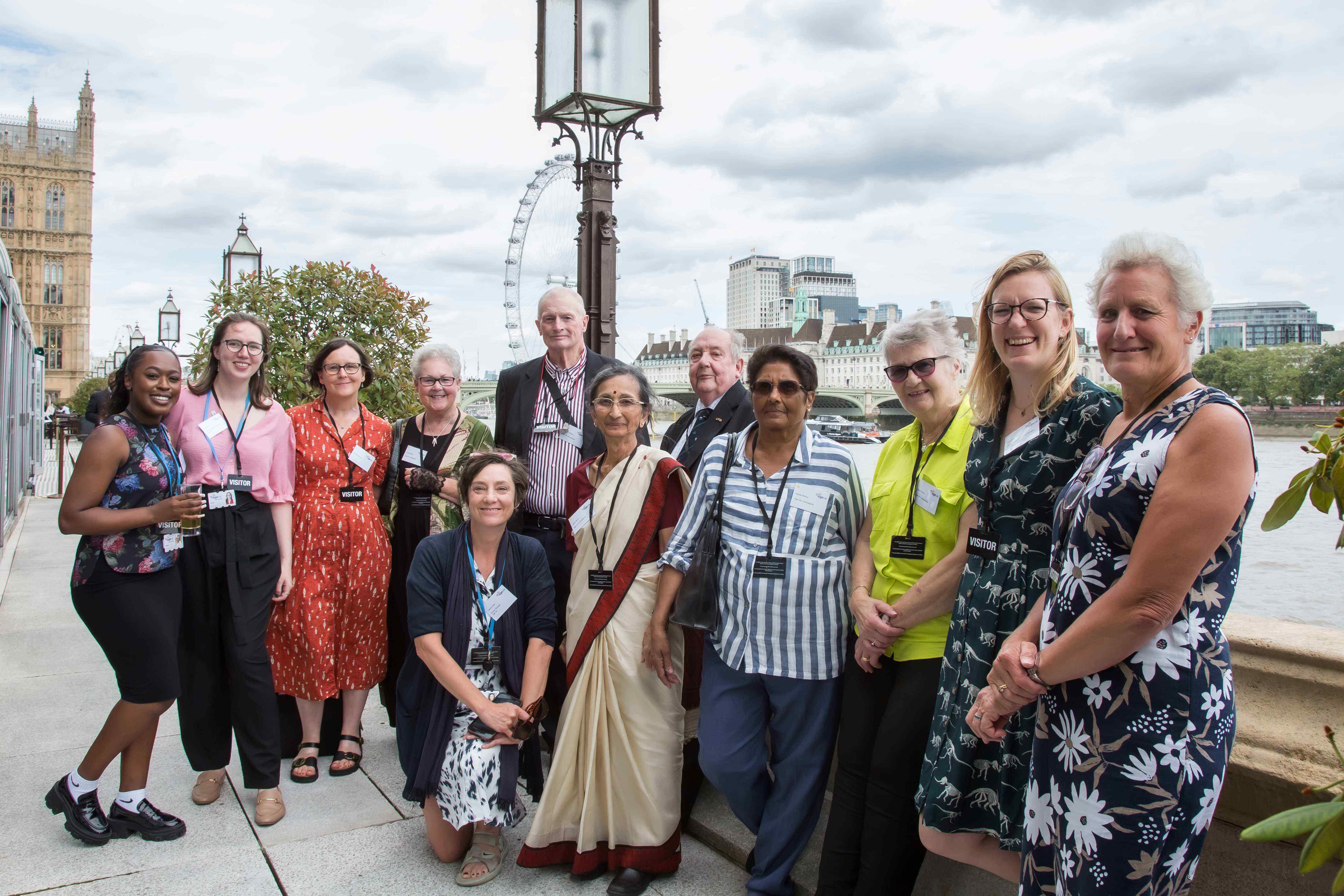 Group of people standing on the terrace outside the House of Commons. London Eye in the background.