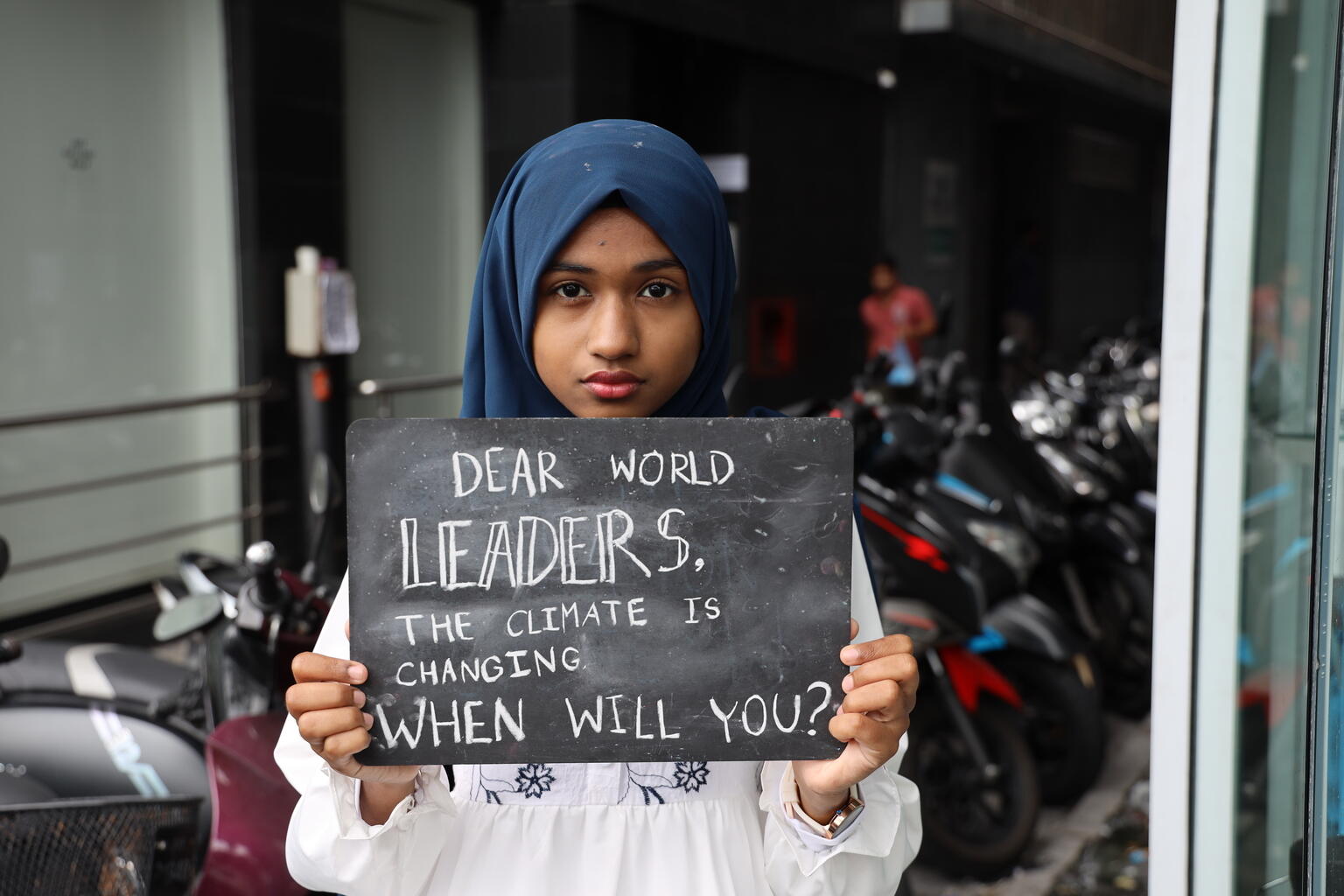 Girl holds board saying dear world leaders, the climate is changing when will you?